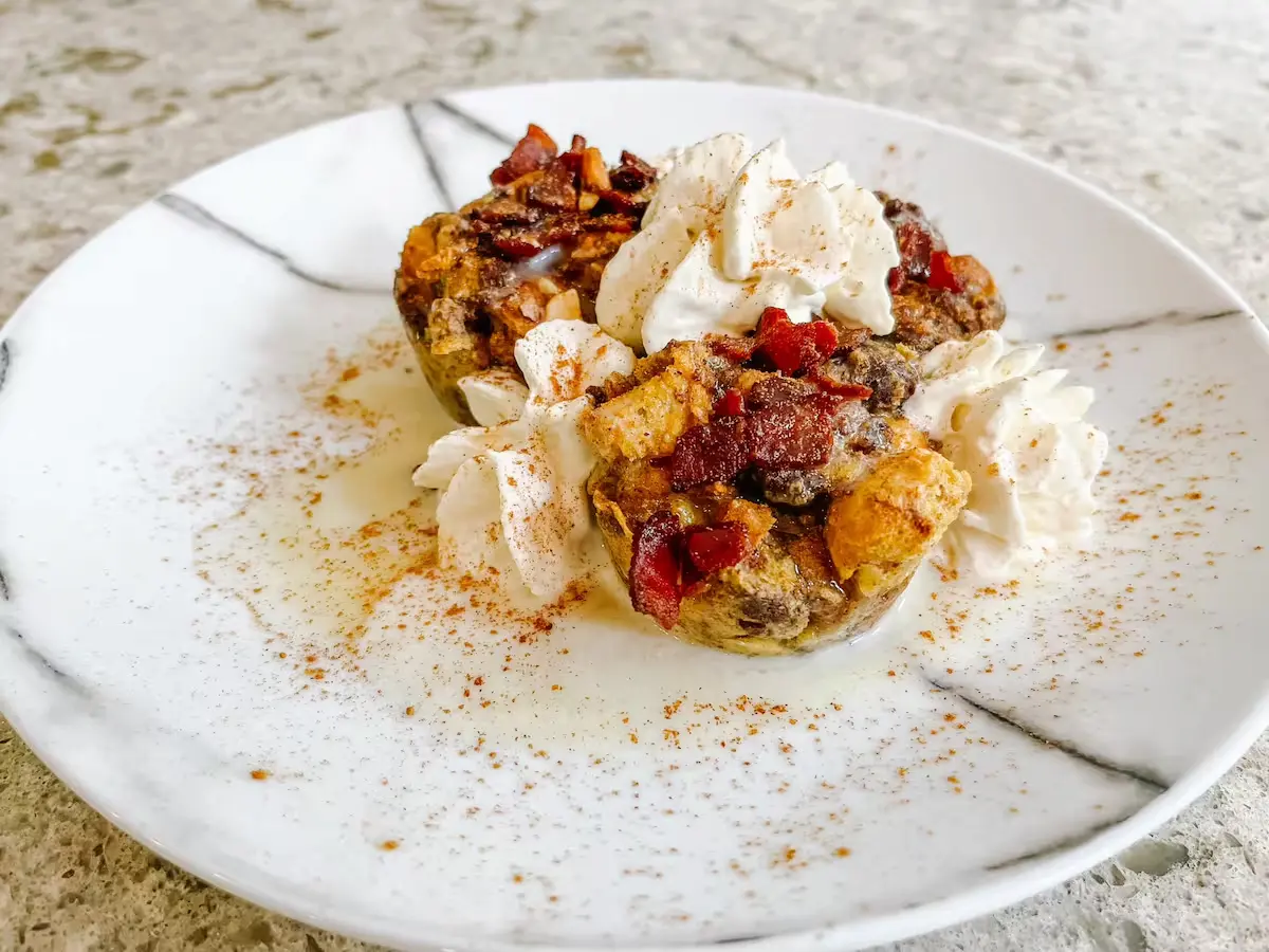 A dessert on a plate, elegantly topped with fluffy whipped cream and crunchy bacon, offering a delightful blend of flavors.