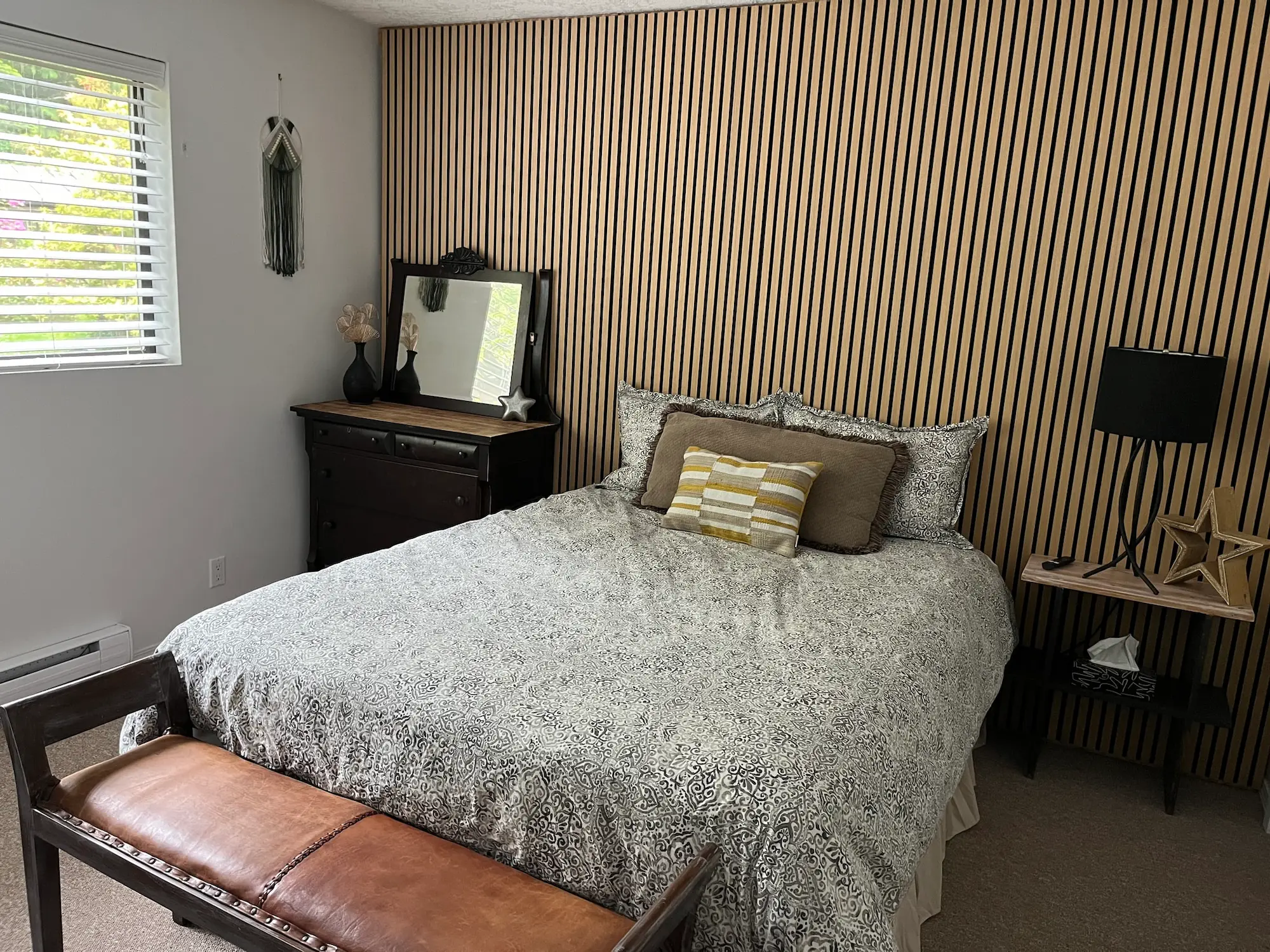 A serene bedroom scene showcasing a comfortable bed, a modern dresser, and a decorative wall panel enhancing the ambiance.