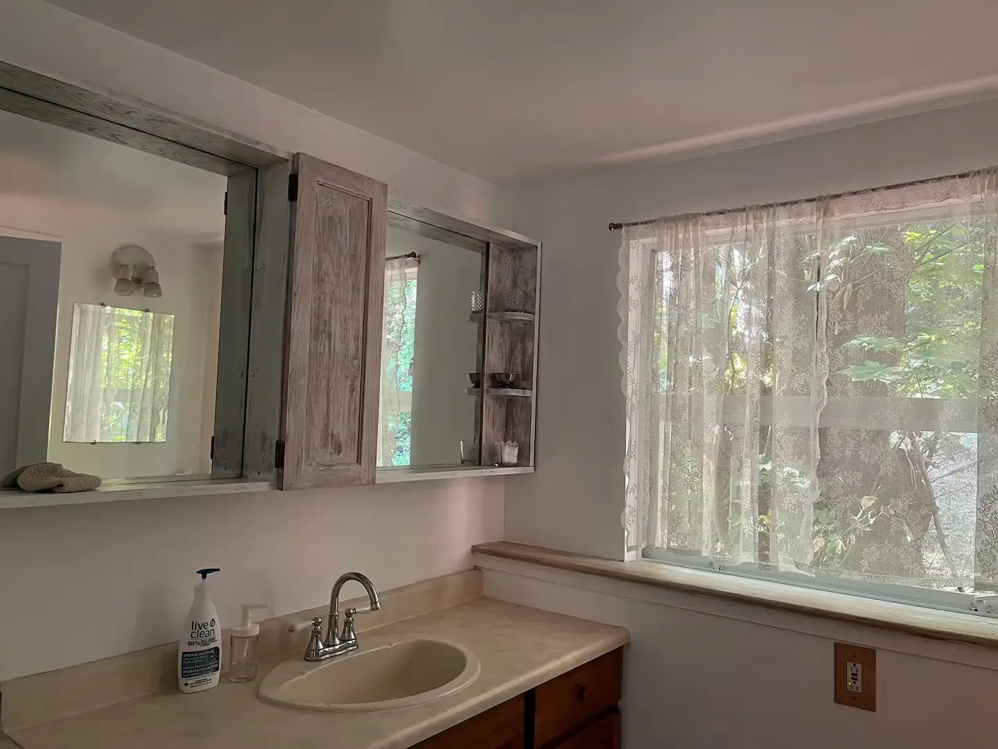 A well-lit bathroom showcasing a sink, a reflective mirror, and a window that enhances the room's ambiance.
