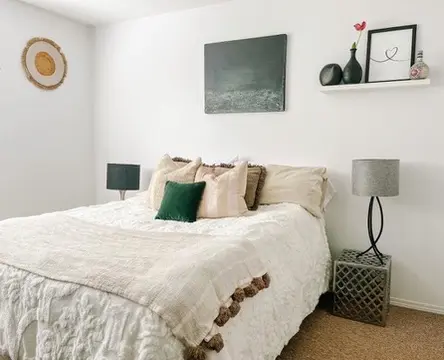 A serene bedroom scene showcasing a bed, a nightstand, and an artwork displayed on the wall.